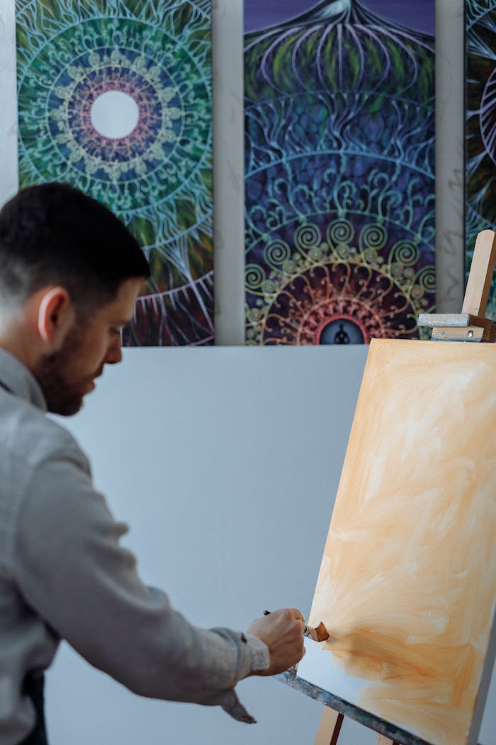 A focused male artist working on a canvas in a creative studio setting.